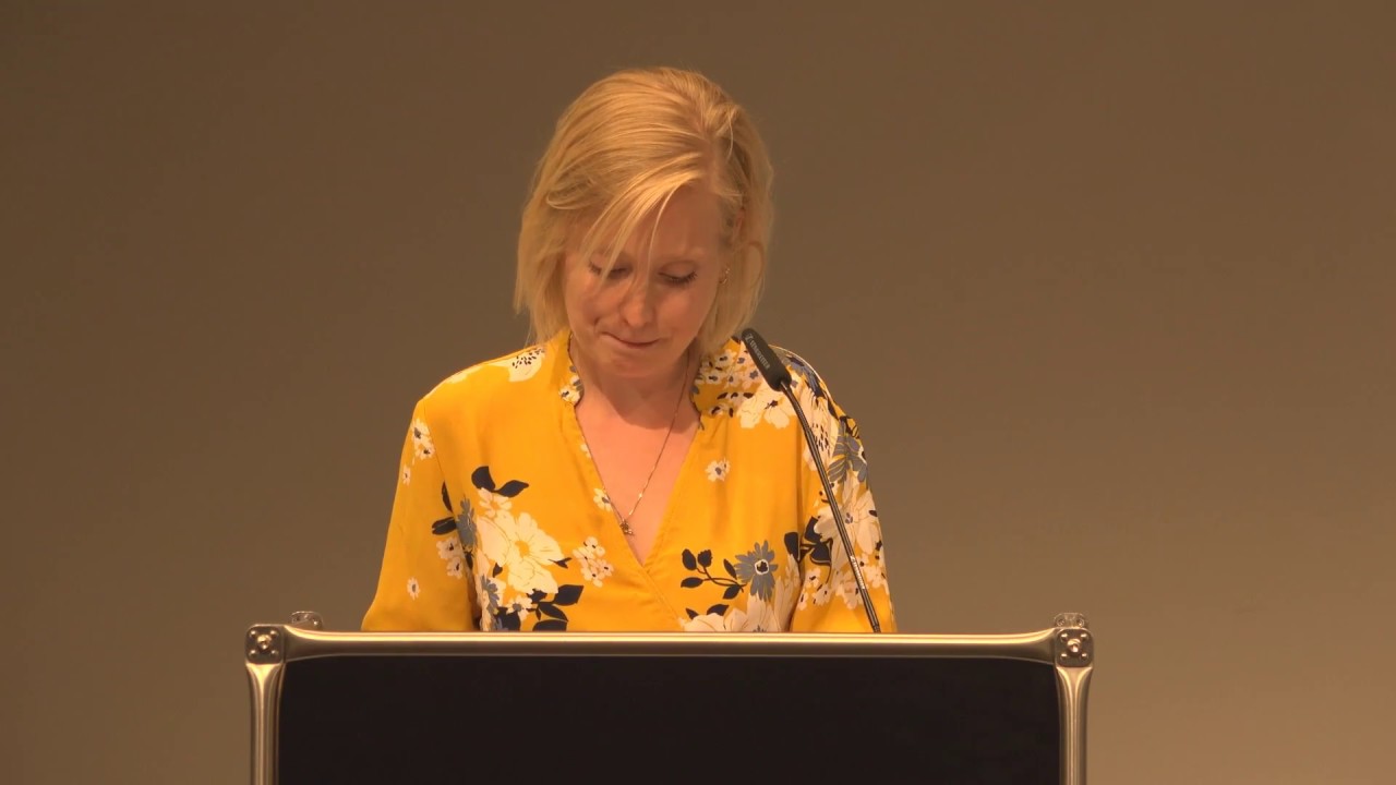 Woman at lectern gives a lecture.