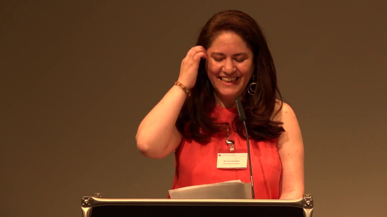 Woman at lectern gives a lecture.