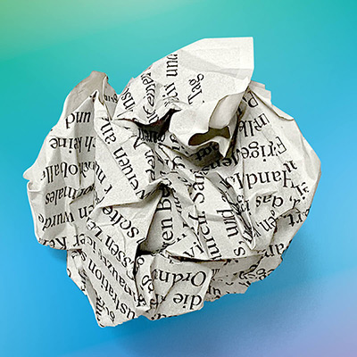 Crumpled printed piece of paper formed into a ball, against a background with yellow-blue-green-purple gradient.