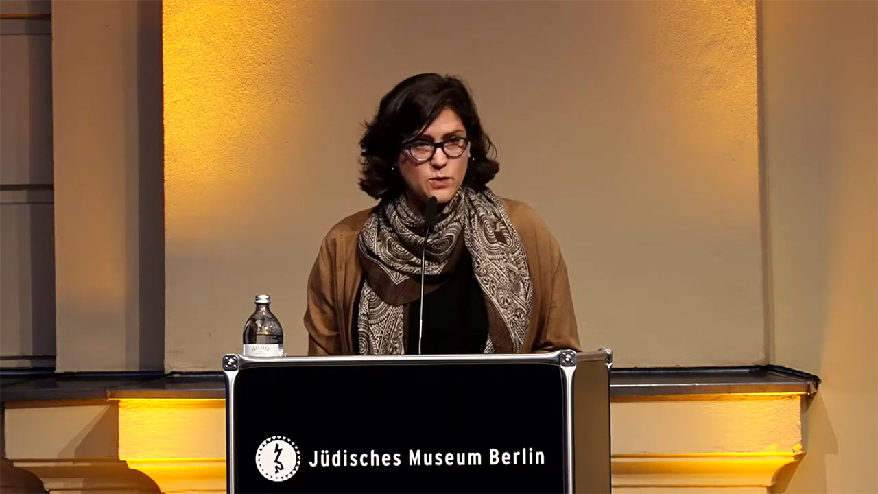 Woman at lectern gives a lecture.