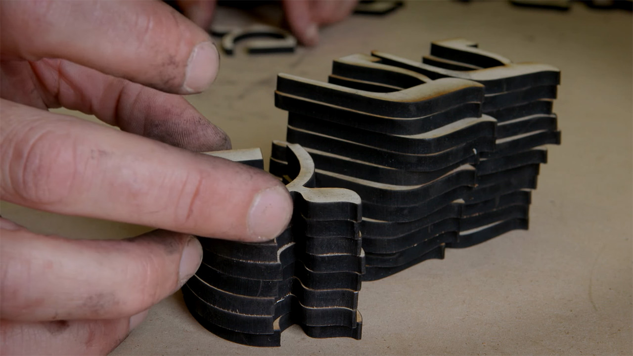 Hände legen hebräische Buchstaben aus Holz übereinander.