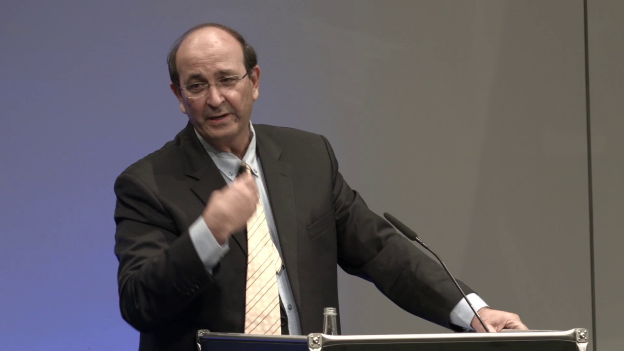 Man at lectern speaks in front of audience.