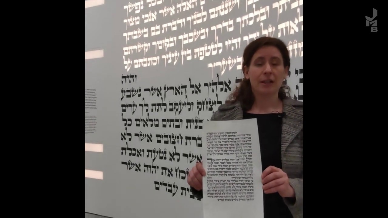 Frau hält einen Zettel mit hebräischen Text in die Kamera.