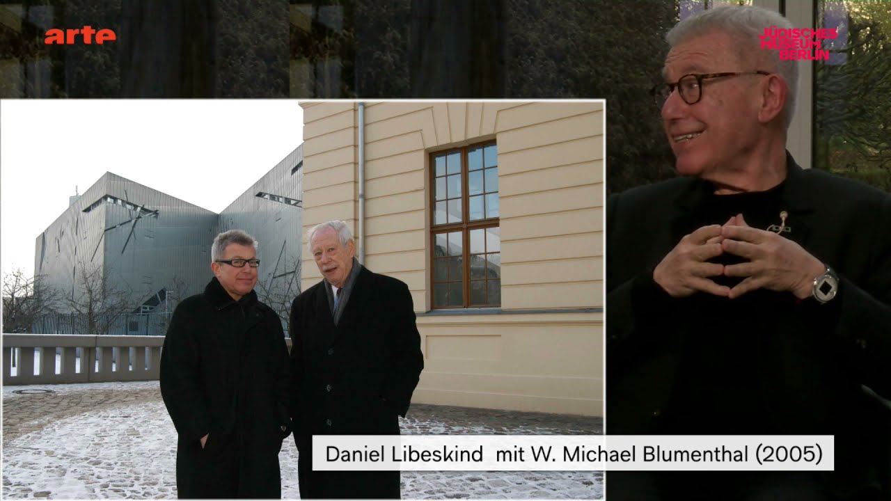 Two men stand talking in the garden of the Jewish Museum Berlin.