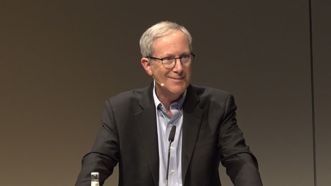 Man in suit at a lectern.