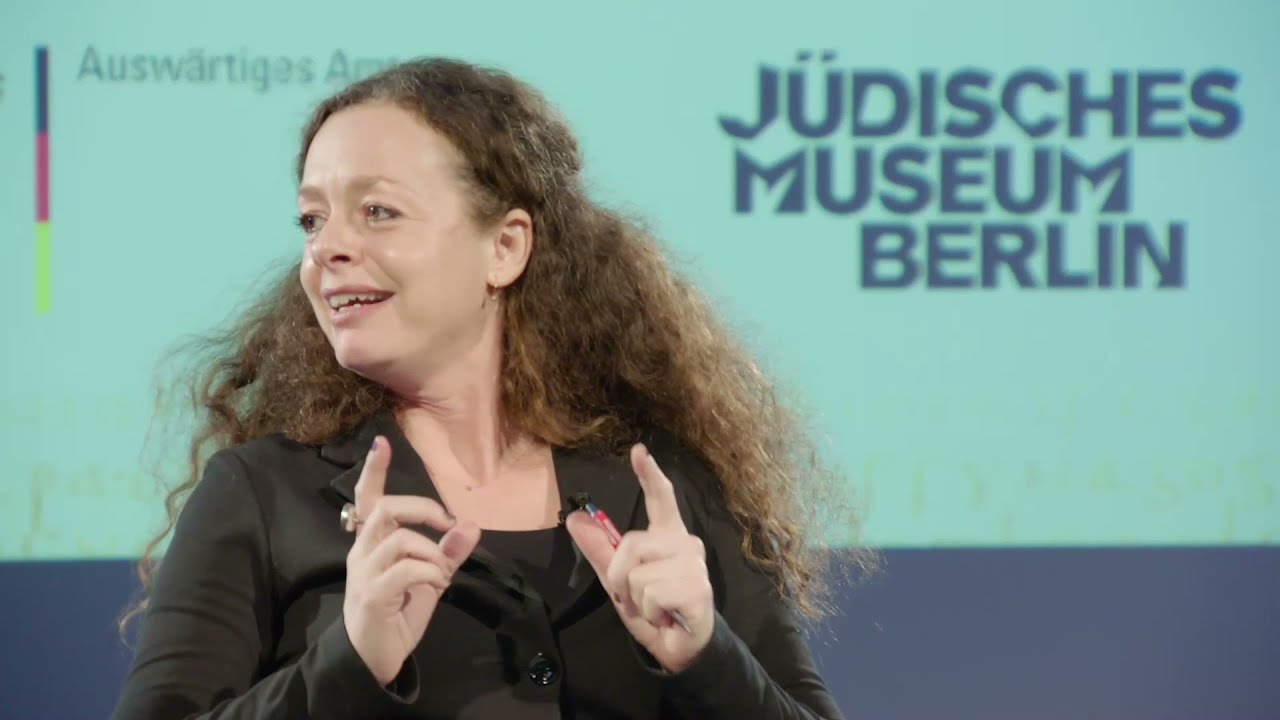 A woman converses gesticulating with both hands.