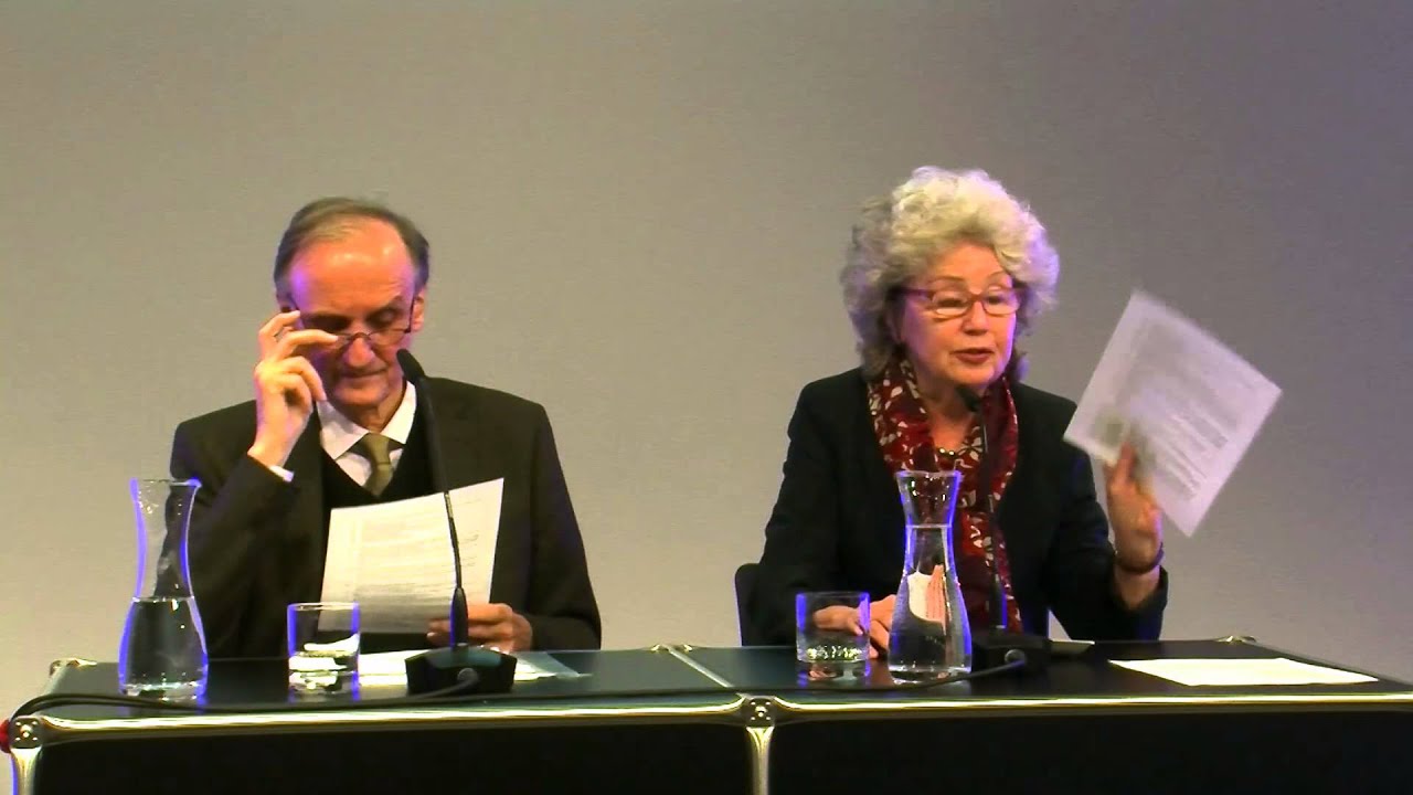 A man and a woman at a table are giving a lecture.