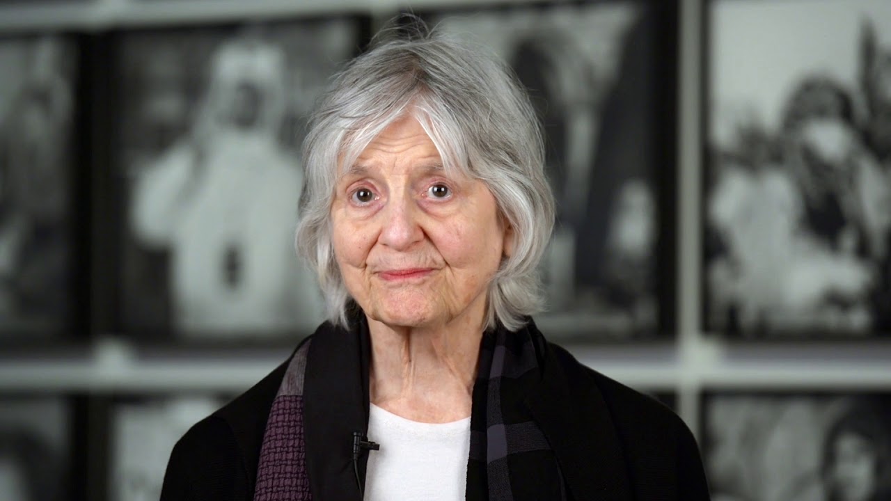 Woman with white hair looks friendly into camera.