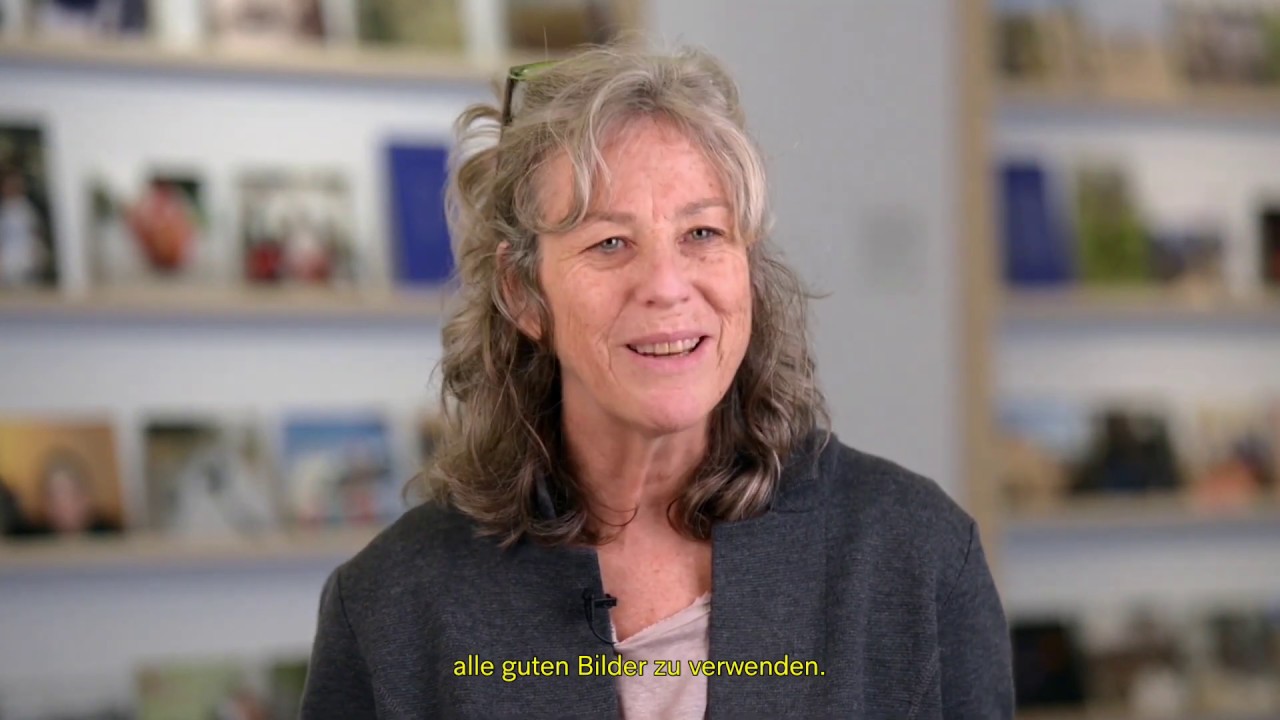 Woman sitting in front of a bookshelf giving an interview.