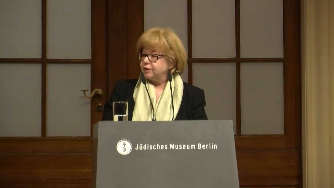 Woman at lectern speaks in front of audience.