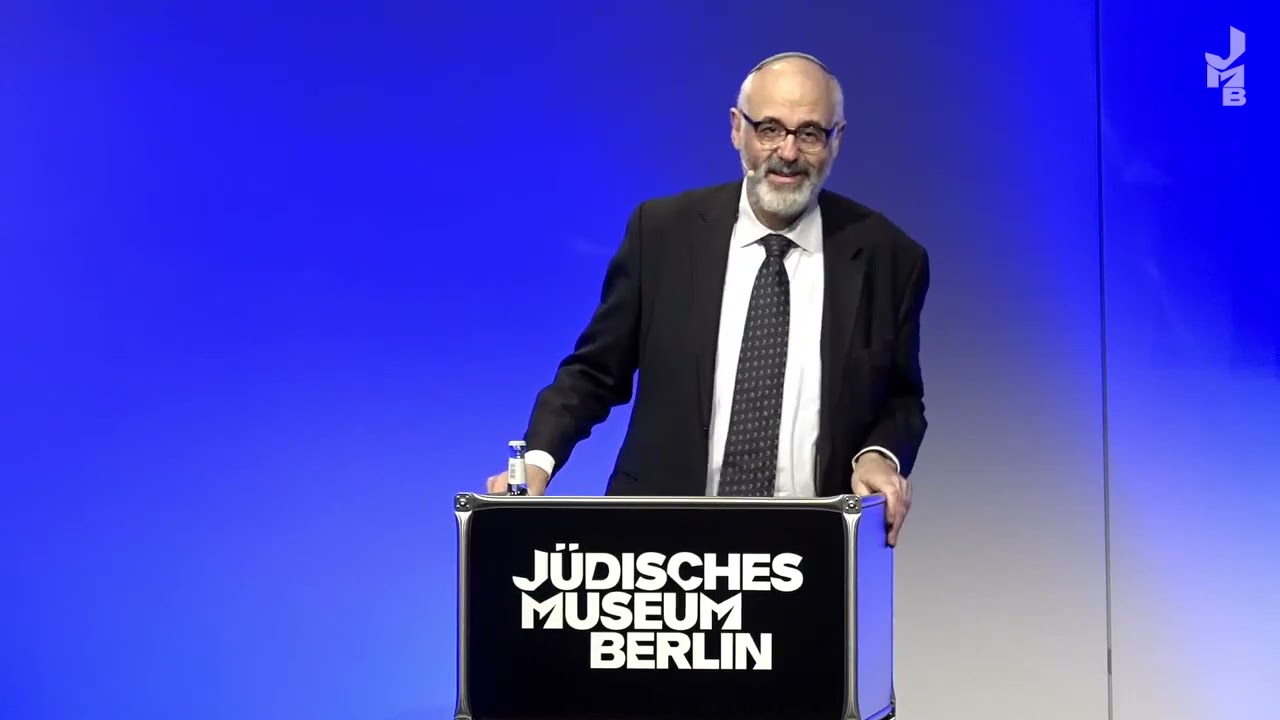 Man standing at a lectern giving a lecture.