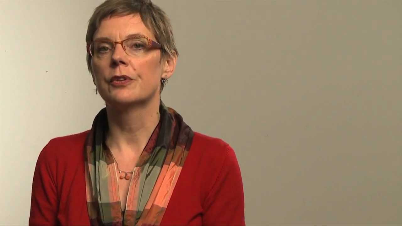 Woman with short haircut and glasses speaks into the camera.