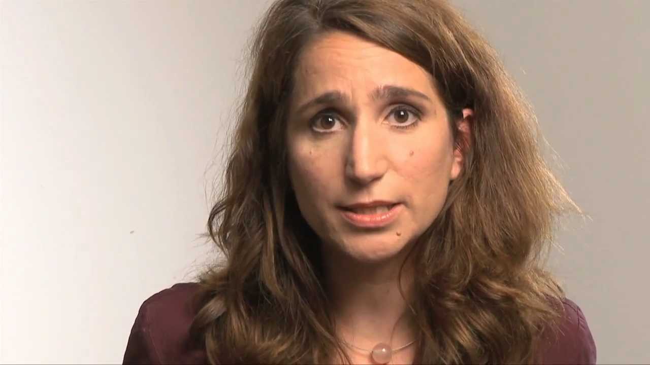 Woman with reddish long hair speaks into the camera.