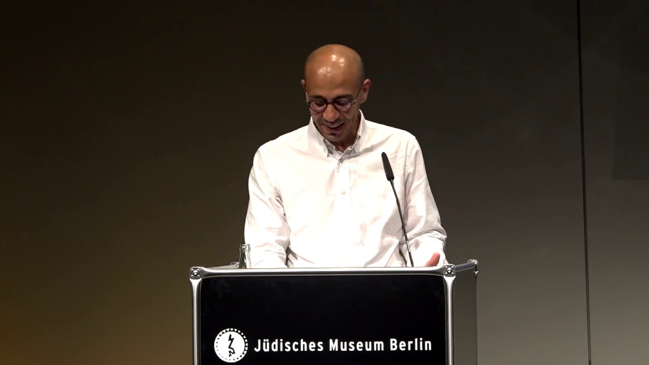 A man stands at the lectern and looks at his manuscript.