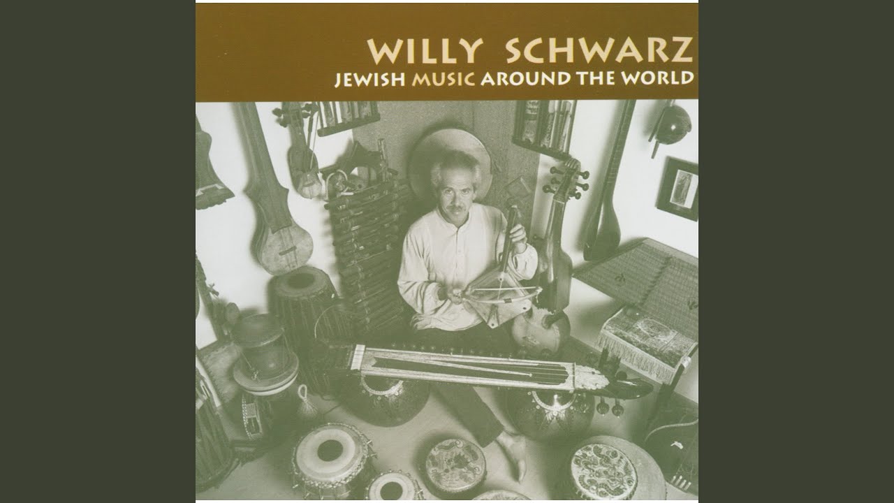 Black and white photograph of a man sitting in a room full of instruments. Above it is the writing "Willy Schwarz Jewish Music Around the World".