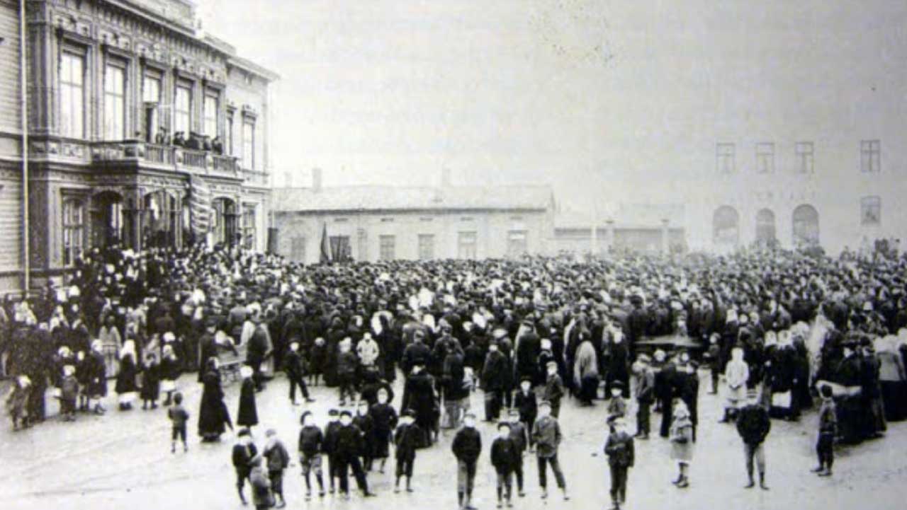 Black and white photograph showing a crowd of people in a large city square.