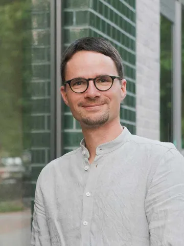 Mann mit Brille schaut freundlich in die Kamera.