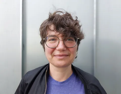 Eine Frau mit krausem, kurzem Haar und Brille schaut freundlich in die Kamera.