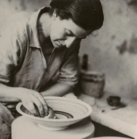 Woman working a clay plate on a turntable.