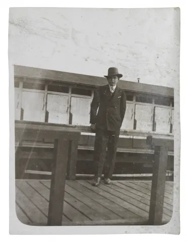 Black-and-white photo of a teenager standing on a wooden walkway