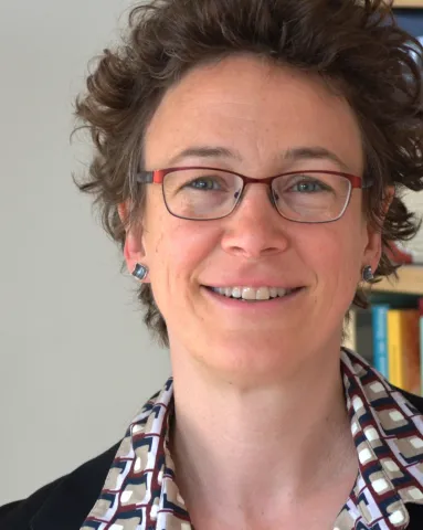 Eine Frau lacht in die Kamera. Sie tr&auml;gt eine Brille.