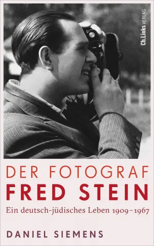 Buchcover mit einem Schwarz-Wei&szlig;-Bild eines Mannes, der durch eine Kamera schaut, und dem Titel: Der Fotograf Fred Stein.