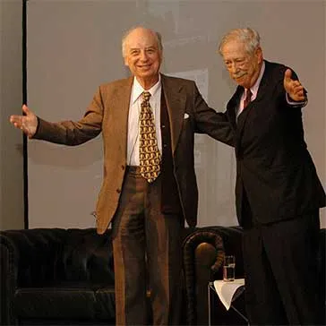 Zwei &auml;ltere Herren (Horst Eisfelder links, W. Michael Blumenthal rechts) in Anzug stehen nebeneinander auf einer B&uuml;hne. Sie sind dem Publikum zugewandt und halten sich locker im Arm.