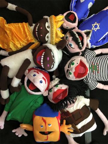 Eight colorful, mouth-moving hand puppets lying in a circle with their heads to the center, laughing at the onlookers.