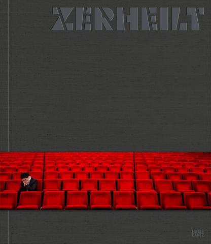 Gray book cover with the title ZERHEILT and a banderole with a photo of a person sitting alone in the red audience seats of a theater