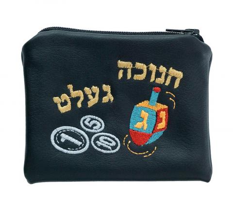 Ein schwarzer Geldbeutel, auf den ein Dreidel, Münzen und in hebräischen Buchstaben das jiddische Wort „Chanukka-Gelt“ gestickt ist.