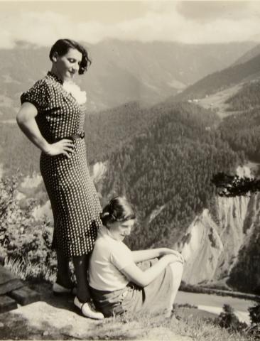 A woman standing behind her daughter, the background show a mountain panoramic view