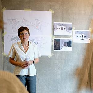 A woman stands in front of a wall with designs of the Liebeskind building.