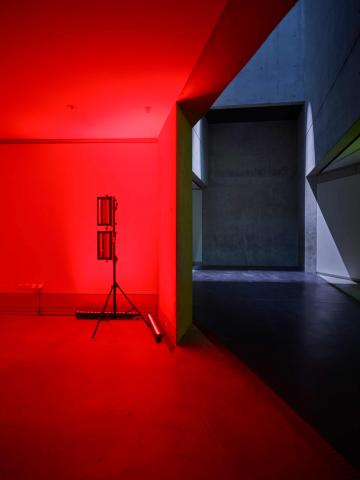 Light illuminates the left side of the room in red, on the right you see the grey of the walls