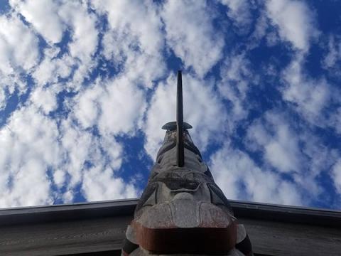 Photography of a totem pole in front of a cloudy sky 