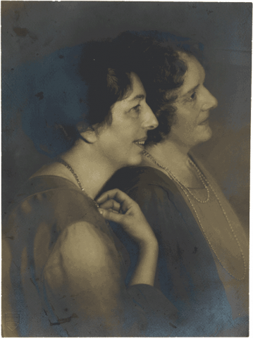 Historical black-and-white photograph of two women in profile leaning against each other.