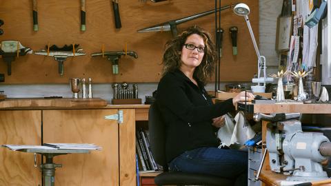 Portrait of Paula Newman Pollachek in front of a wooden wall with tools