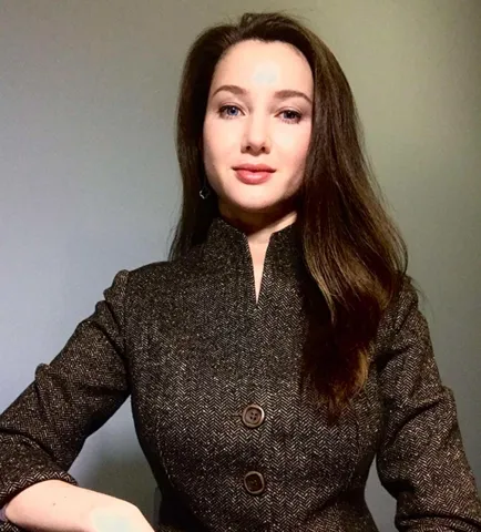 Woman with dark long hair looks friendly into the camera.