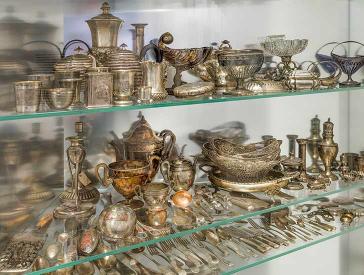 Glasvitrine voller Geschirr, Besteck und sonstiger Gegenstände aus Silber