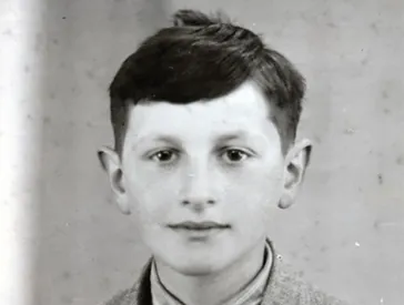 Black and white photo: Portrait of a dark-haired boy. He looks friendly into the camera.