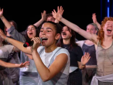 A group of people are singing with their hands in the air.
