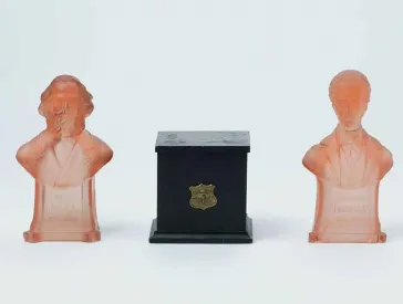 Zwei B&uuml;sten aus rotem, durchsichtigem Glas. Die linke zeigt Karl Marx, die rechte Ferdinand Lassalle. Dazwischen eine dunkelbraune Spieluhr aus Holz.