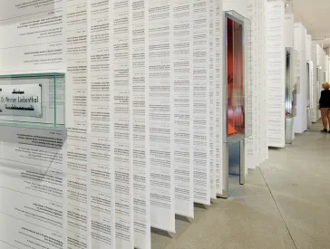 Eine Person betrachtet eine Reihe von der Decke herabh&auml;ngender langer Banden mit Schrift darauf