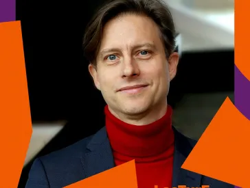 Graphic with red and purple elements around the edge; the photo shows a man in a jacket and red turtleneck sweater.