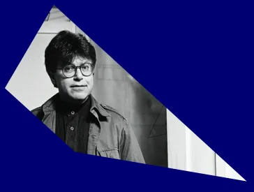 Schwarz-wei&szlig;-Portr&auml;t von Daniel Libeskind in den 1980er Jahren mit Brille, umgeben von einem schr&auml;gen blauen Passpartout.