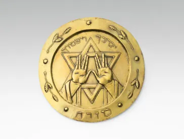 Gold-colored plate with Hebrew script, Star of David and two hands.