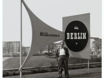 Fred Stein, behind him a sign reading &ldquo;Welcome to Berlin.&rdquo;