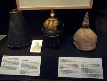 Pickelhaube (spiked helmet) with camouflage covering and hatbox in a showcase
