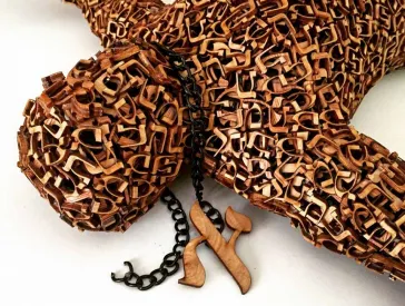 Eine Holzfigur auf hebräischen Buchstaben mit einer Kette um den Hals.