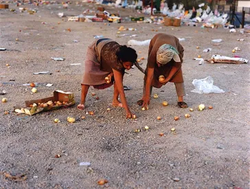 Künstlerisch inszeniertes Foto: Zwei weibliche Figuren sammeln übriggebliebene Zwiebeln vom Boden auf.