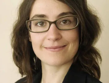 Portrait of a woman with glasses who smiles and looks directly into the camera